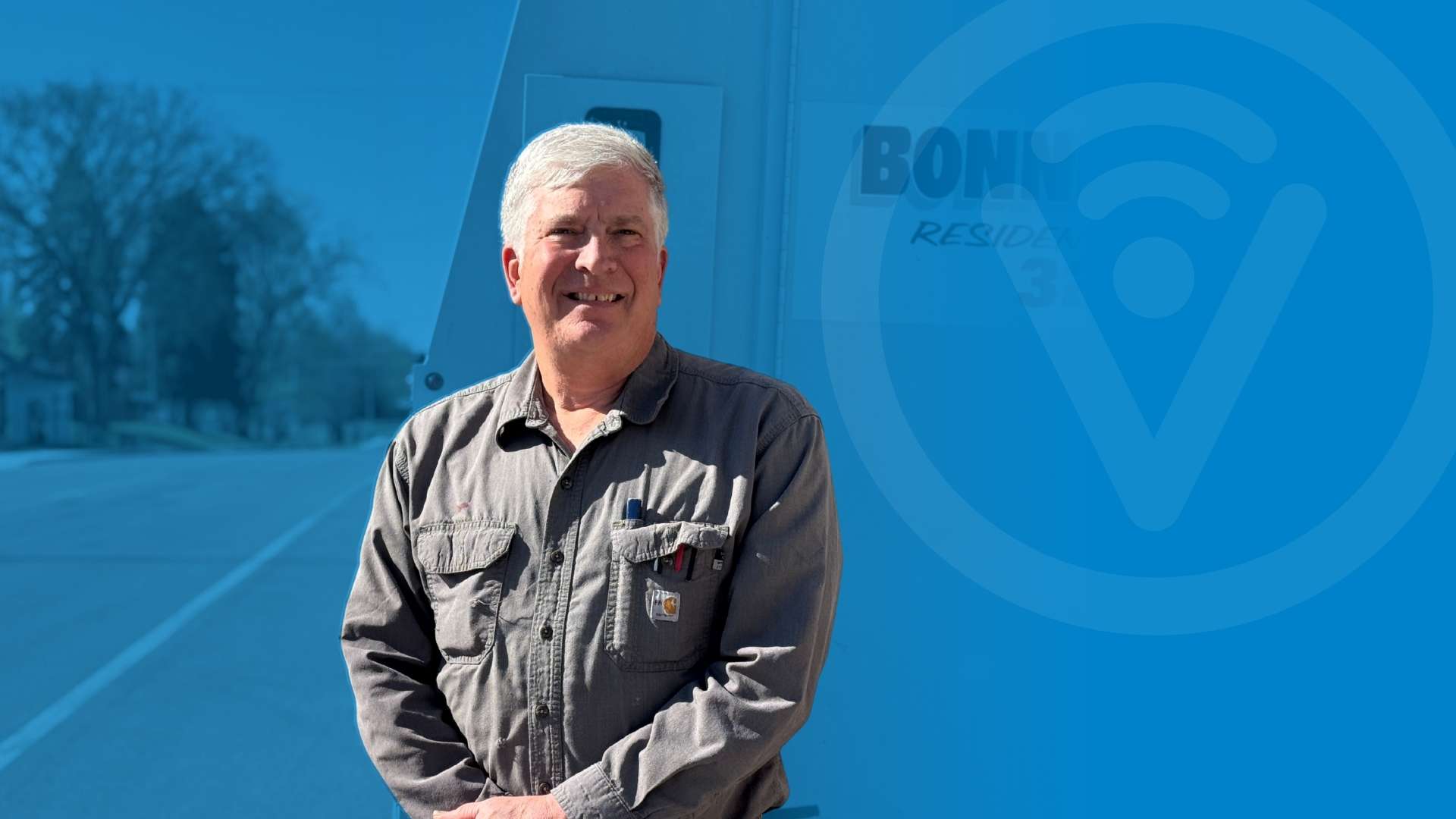 Person leaning against a truck and smiling.